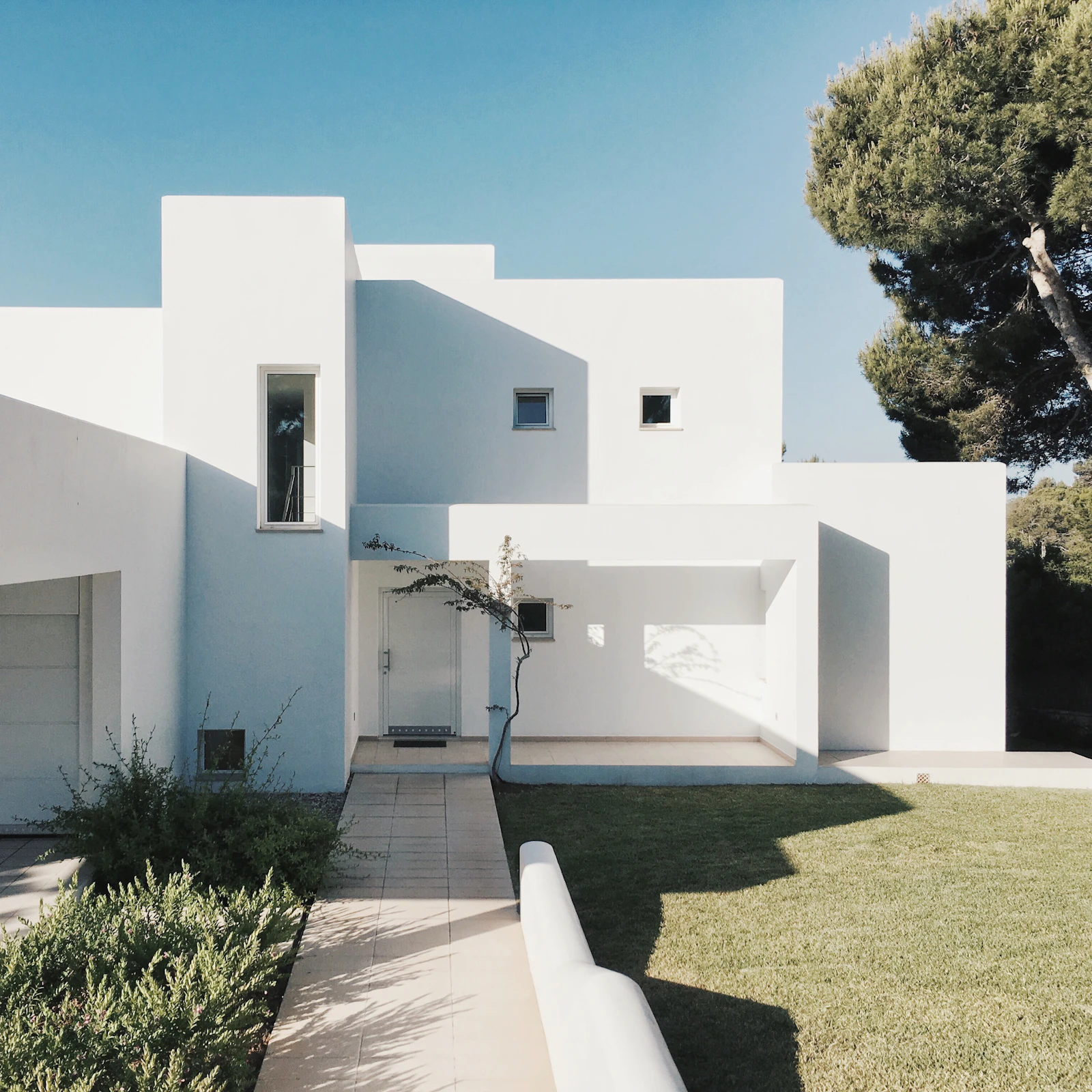 White rendered modernist home with a landscaped courtyard